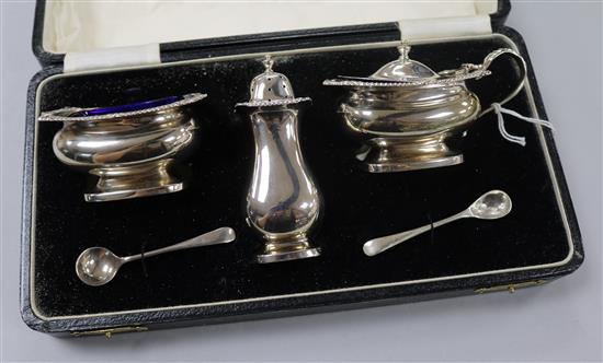 A cased silver three piece condiment set with two silver spoons.